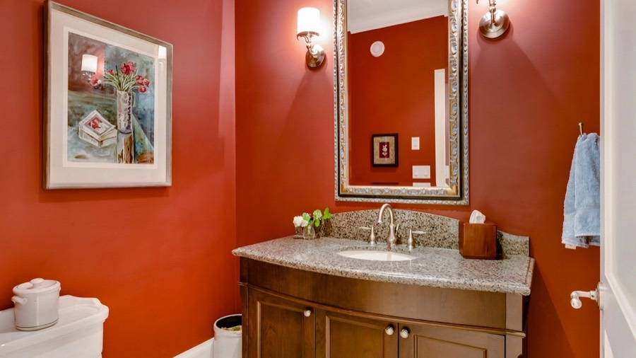 A bathroom before redesign, with a dark red wall and a heavy oak vanity